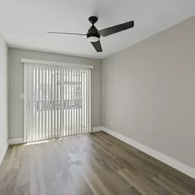 an empty living room with sliding glass doors and a ceiling fan
