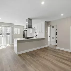 a renovated living room and kitchen with white walls and wood floors