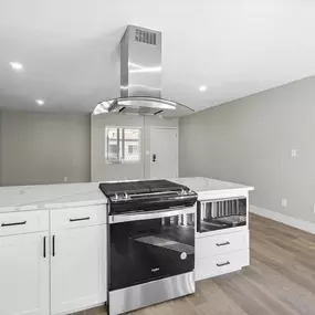 a kitchen with white cabinets and a stove and a hood