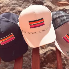 Three 'The Agriculturalist' branded hats displayed on a wooden chair at The Agriculturalist