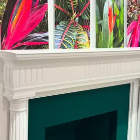 White decorative mantel with a teal interior, topped with vibrant tropical plant artwork at The Agriculturalist Dispensary