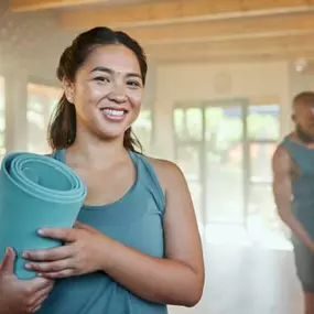 Smiling young Asian woman with yoga mat after GLP-1 wellness session at The Maxim Clinic, Marietta GA