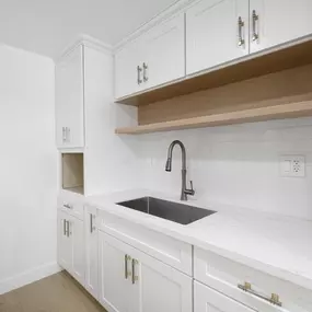 A kitchen with white cabinets and a black sink.