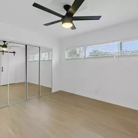 A room with a ceiling fan and a sliding glass door.