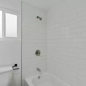 A white bathroom with a tub and toilet.