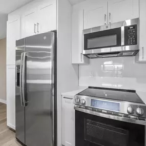A modern kitchen with a stainless steel refrigerator and oven.