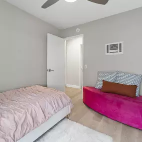 A bedroom with a pink bed and a pink bench.