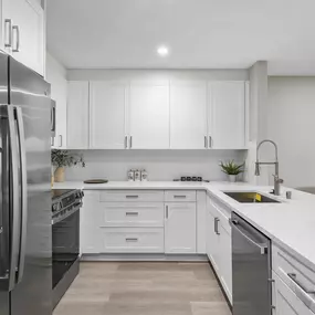 A modern kitchen with a stainless steel refrigerator and white cabinets.