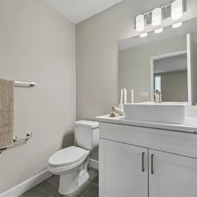 A white bathroom with a toilet, sink, and mirror.