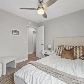 A bedroom with a bed, pillows, and a ceiling fan.