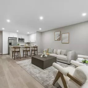 A modern living room with a kitchen in the background.