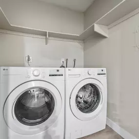Two white front loading washing machines in a laundry room.