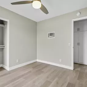 A room with a ceiling fan and a door leading to another room.
