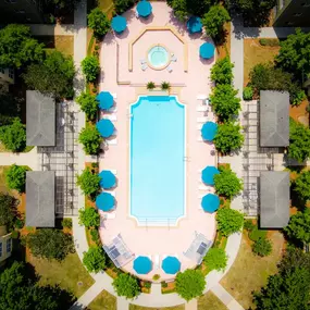 An aerial view of a pool surrounded by trees and buildings