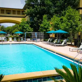 A large swimming pool surrounded by trees and lounge chairs
