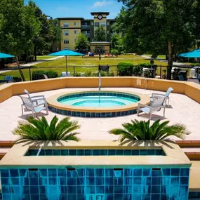 A pool surrounded by a patio and trees