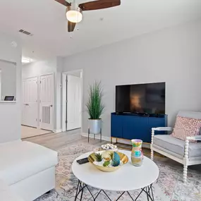 A living room with a white couch, a white coffee table, a blue cabinet, and a ceiling fan