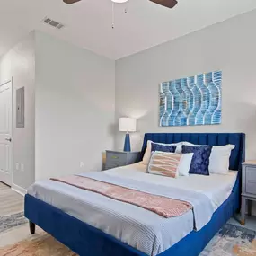 A bedroom with a bed, nightstand, and ceiling fan