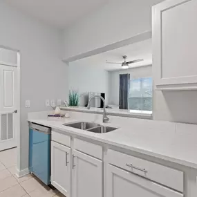 A kitchen with white cabinets and a blue trash can