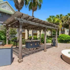 A wooden pergola is over a hot tub in a courtyard