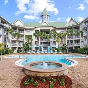 Swimming pool and hot tub surrounded by a sundeck and greenery