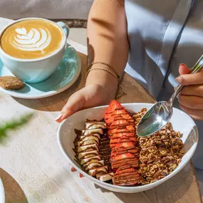 Handcrafted coffee with latte art and a hazelnut crunch acai bowl, served in a warm and welcoming all day café atmosphere.