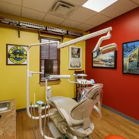 Dental operatory at Dental Depot's Northwest OKC dental clinic with red and yellow walls and train themed pictures on the walls.