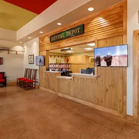 Reception area at Dental Depot's Northwest OKC office with red furniture, light colored wood accents, and a model train track.