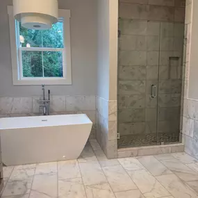 Finished bathroom remodel featuring a spacious walk-in shower, freestanding tub, and elegant stone tile finishes.