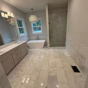 High-end bathroom remodel featuring a double sink vanity, walk-in shower, and polished marble flooring.