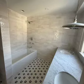 Bathroom with a shower-tub combo, featuring large format wall tiles, built-in niches, and mosaic tile accents for a modern touch.