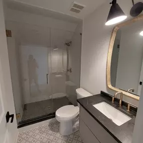 Contemporary bathroom remodel featuring a frameless glass shower, wall-mounted vanity, and backlit mirror for a sleek, modern look.