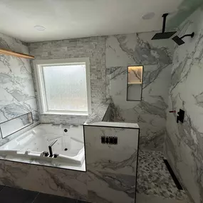 Luxurious bathroom upgrade with marble finishes, whirlpool tub, walk-in shower, and matte black fixtures.