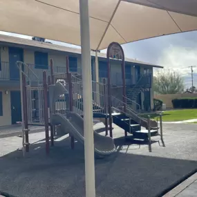 A playground with a slide and a red backpack on the ground.
