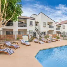 outdoor pool with wooden deck chairs with white and blue comforter covers
