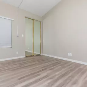 apartment bedroom interior with hardwood floors with closet mirror and window