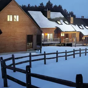 A picturesque exterior view of multiple cabins covers in snow at Christmas Mountain Campground