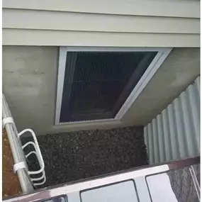An exterior view of a brand new egress window installation before the grate and polycarbonate cover are installed.