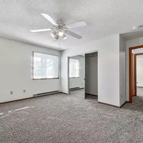 an empty living room with a ceiling fan