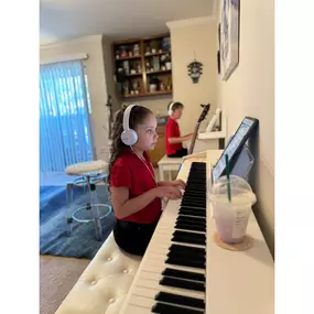 This photo captures a focused and immersive Baney Jones Music Studio music lesson. Young students are deeply engaged in their piano practice, wearing Sony headphones. They concentrate on their pieces and refine their skills in a structured, distraction-free environment.