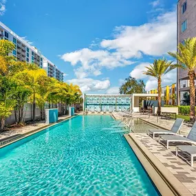 A swimming pool at a hotel with palm trees and chairs