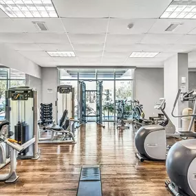 A gym with cardio machines and a wood floor