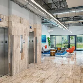 The lobby of a building with elevators and a table and chairs