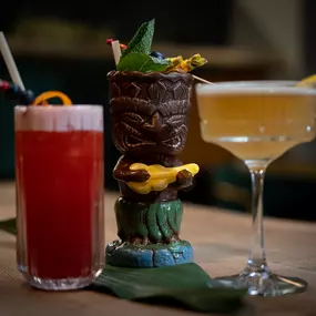Dreier-Set aus kreativen Cocktails: fruchtiger Longdrink, exotischer Tiki-Drink und eleganter Sour-Cocktail – kunstvoll angerichtet mit Dekoration.