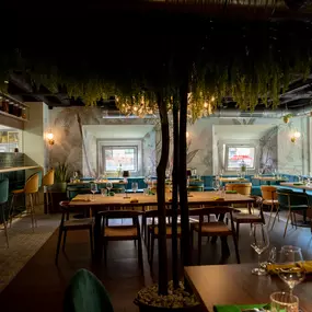 Heller und stilvoll eingerichteter Restaurantbereich mit großflächigen Sitzbereichen, Pflanzenakzenten und moderner Lichtgestaltung – ein Ort zum Wohlfühlen.