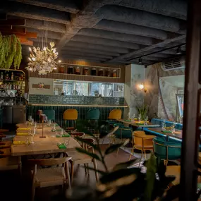 Einladender Restaurantbereich mit rustikaler Decke, grünem Interior, stilvoll gedeckten Tischen und atmosphärischer Beleuchtung – modernes Ambiente mit Naturflair.