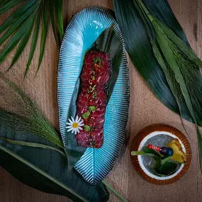 Exotisch angerichtetes Longplate-Gericht mit Thunfischtatar, Edamame und Blüten, serviert auf blauen Keramiktellern mit Dip – tropisch inszeniert.