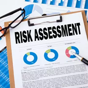 A risk assessment report lies on a clipboard at Ibrahim & Dobaria Law, PLLC. Surrounded by charts, glasses, and a pen, the document showcases data visualization in business evaluation.