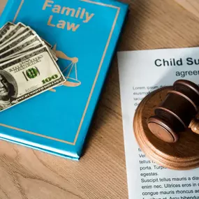 This image from Ibrahim & Dobaria Law, PLLC shows a child support agreement beside a gavel, legal book on family law, and cash, symbolizing legal assistance in family and financial matters.