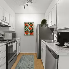Galley kitchen with stainless steel appliances, vinyl plank flooring, and ample storage.